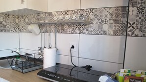 A kitchen with a black induction cooktop, a dish rack, a roll of paper towels, and a basket of coffee.