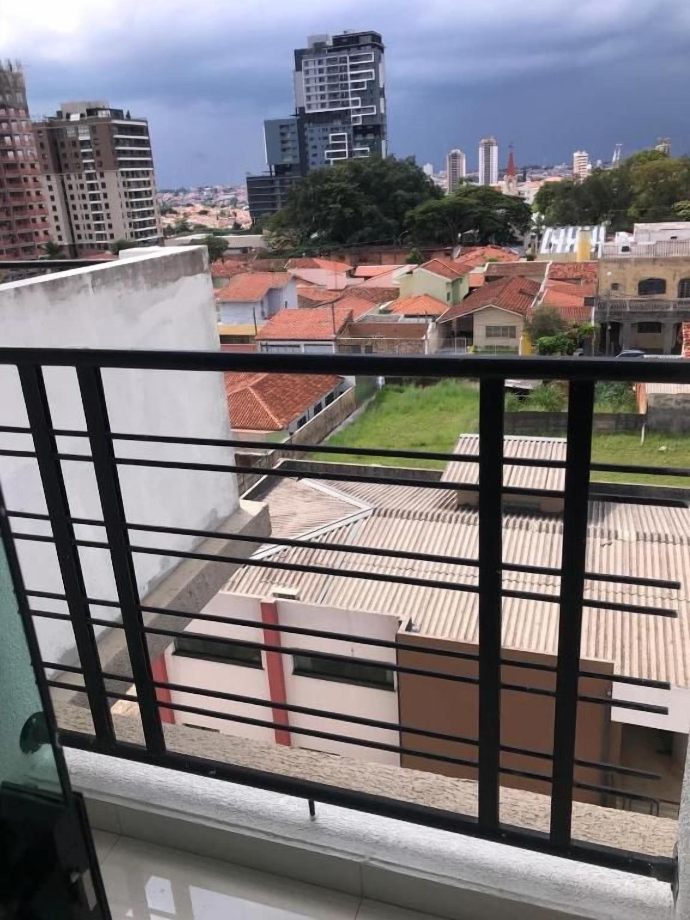 Un balcón con vista a un paisaje urbano, que incluye edificios y un cielo nublado.
