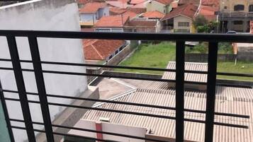Un balcón con vista a un paisaje urbano, que incluye edificios y un cielo nublado.