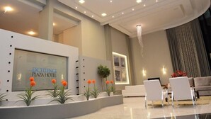 Een moderne hotel lobby met een receptiebalie, een zithoek en een kroonluchter.