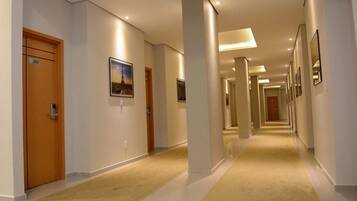 Un pasillo de hotel con piso alfombrado, puertas de madera y cuadros en las paredes.