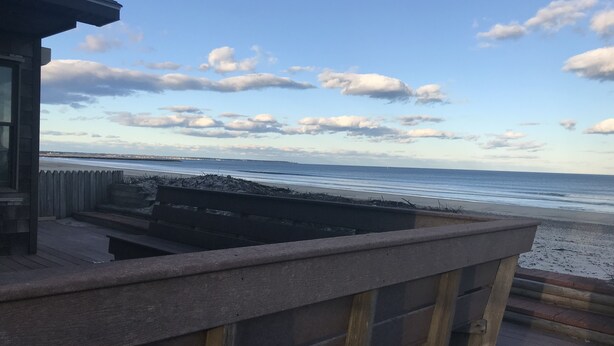 En utsikt över stranden från en balkong med ett träräcke och en betongkant.