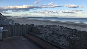 En strandutsikt med ett trädäck och trappsteg som leder ner till en sandstrand.