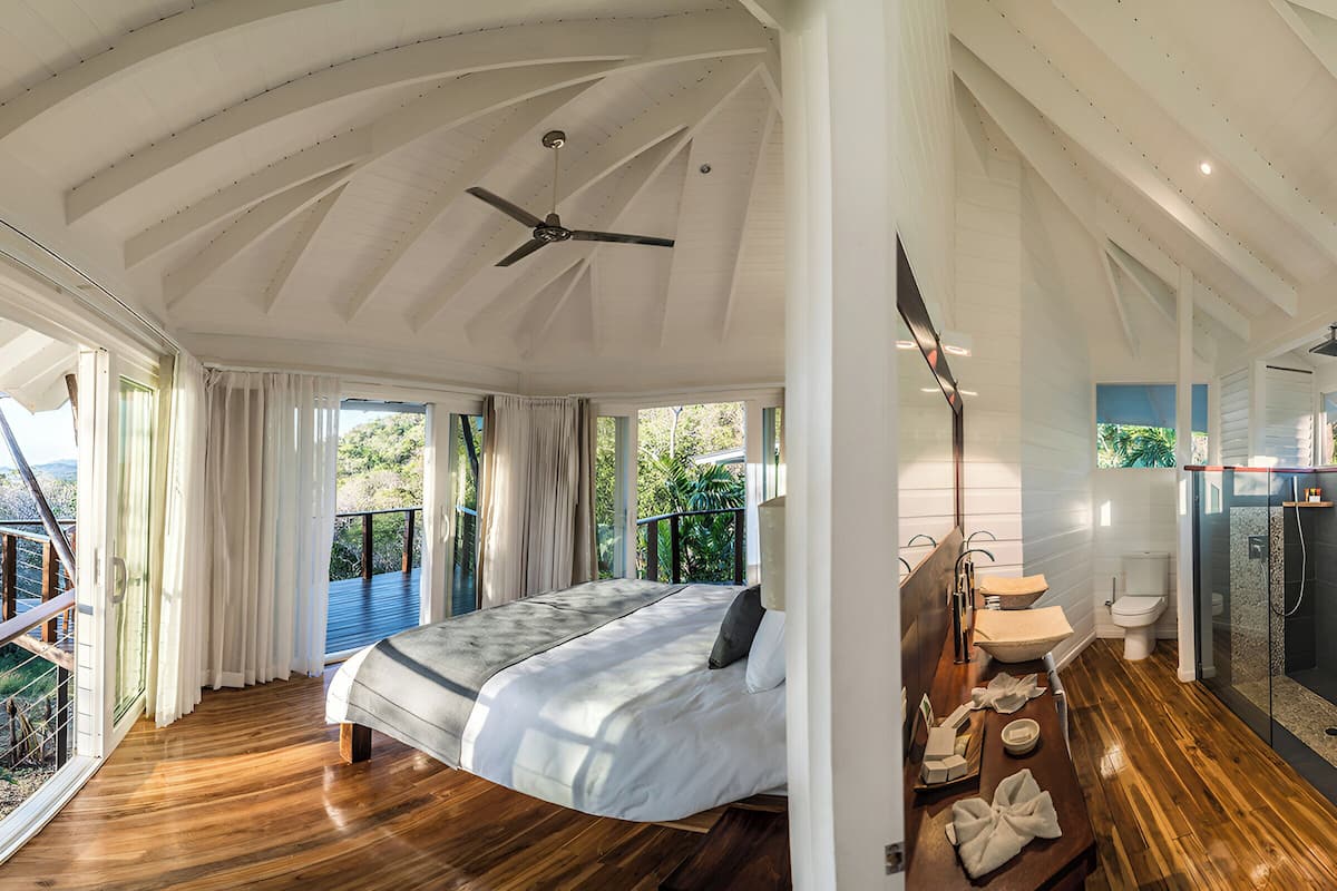 A spacious bedroom with a large bed, a ceiling fan, and a view of the outdoors.