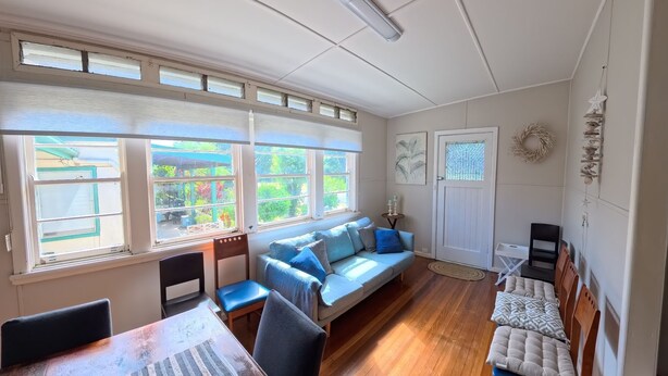A room with a large window, a sofa, a dining table, and a door. - Marlene Court -  Air con, boat parking (South West Rocks)