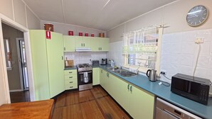 A kitchen with light green cabinets, a stove, a microwave, and a sink. - Marlene Court -  Air con, boat parking (South West Rocks)
