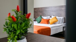 A hotel room with a bed, pillows, a bedside table, and a potted plant. - Boutique Hotel MOJO (Tbilisi)
