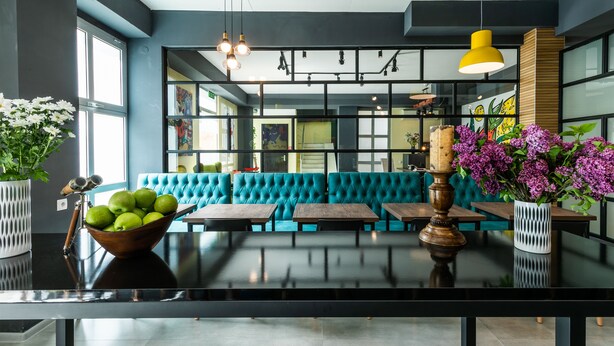 A modern interior with a teal sofa, wooden tables, and a bowl of green apples. - Boutique Hotel MOJO (Tbilisi)