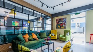 A modern lobby with a green sofa, yellow armchairs, and a coffee table. - Boutique Hotel MOJO (Tbilisi)
