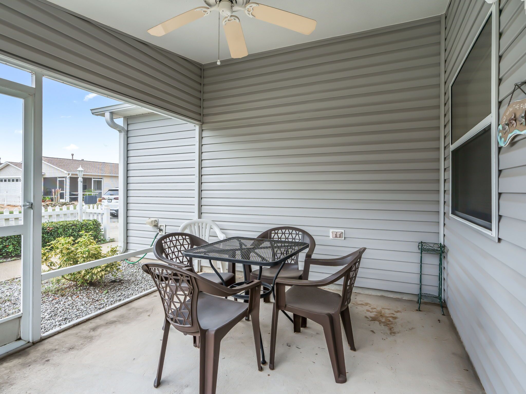 A covered patio with a table and chairs, a ceiling fan, and a view of neighboring houses.