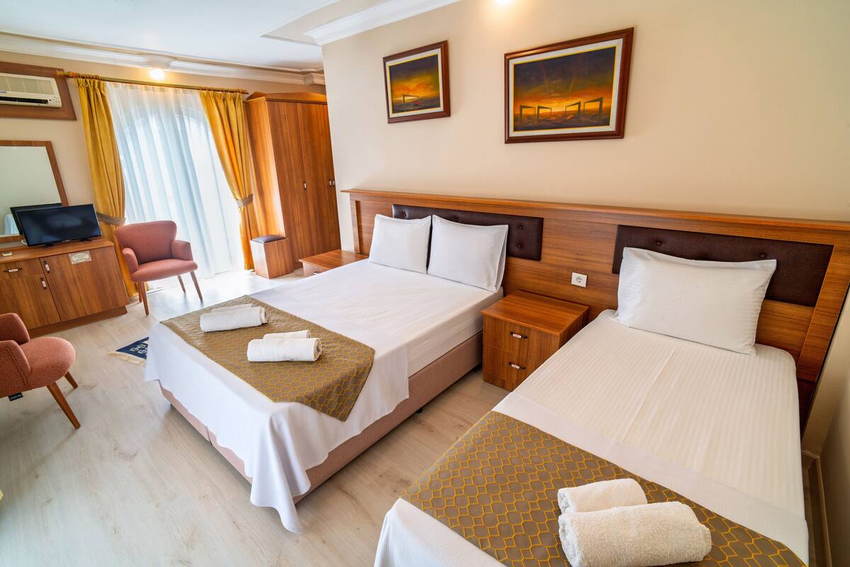 A hotel room with two beds, a desk, a chair, and a television.