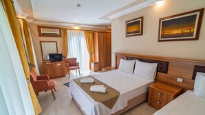 Habitación de hotel con una cama grande, un escritorio con computadora, una silla y un armario.
