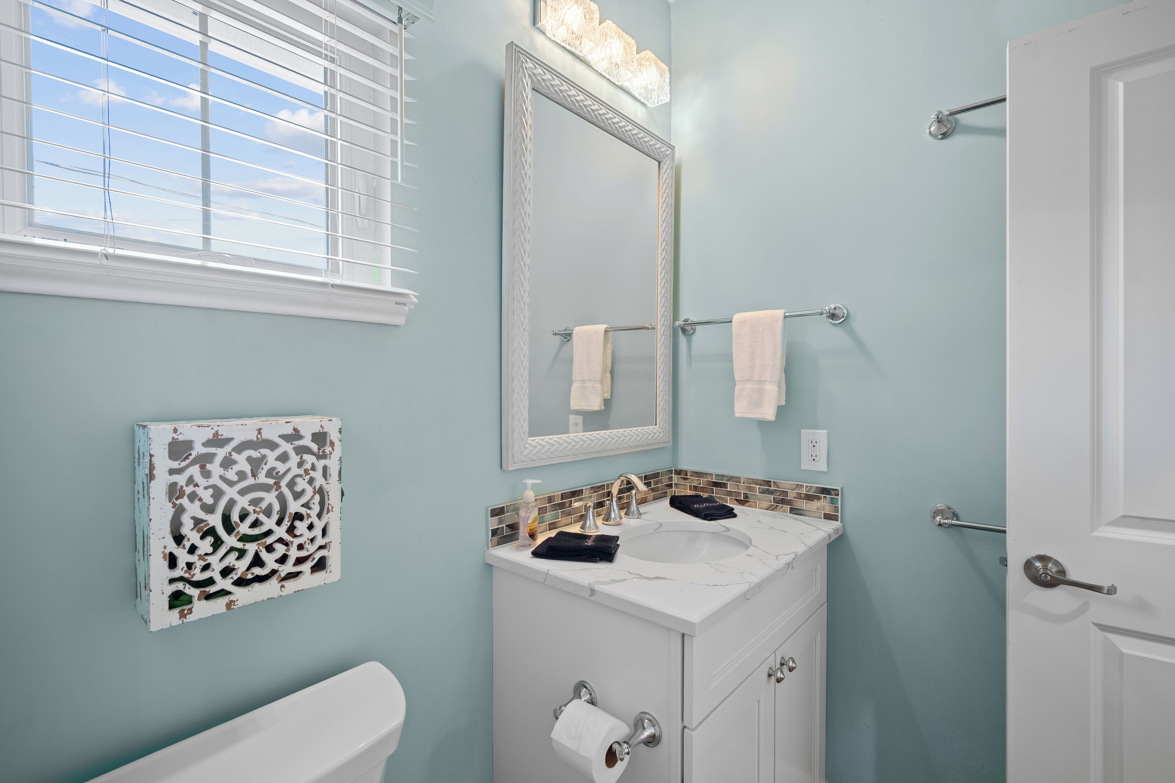 Une salle de bain avec un lavabo blanc, un miroir et des toilettes.