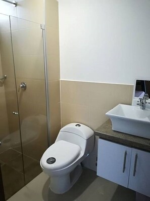 A bathroom with a toilet, a sink, and a shower enclosure.