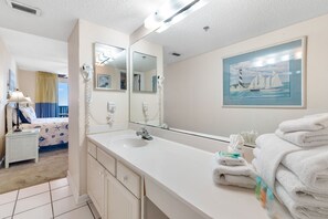 Een hotelbadkamer met een grote spiegel, een wastafel en een schilderij van een zeilboot.