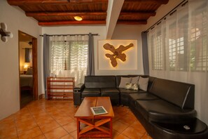 A living room with a black leather sofa, a wooden coffee table, and a large abstract light fixture on the wall.