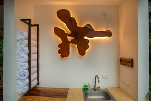 A modern bathroom with a wooden towel rack, a wall-mounted light fixture, and a sink with a faucet.