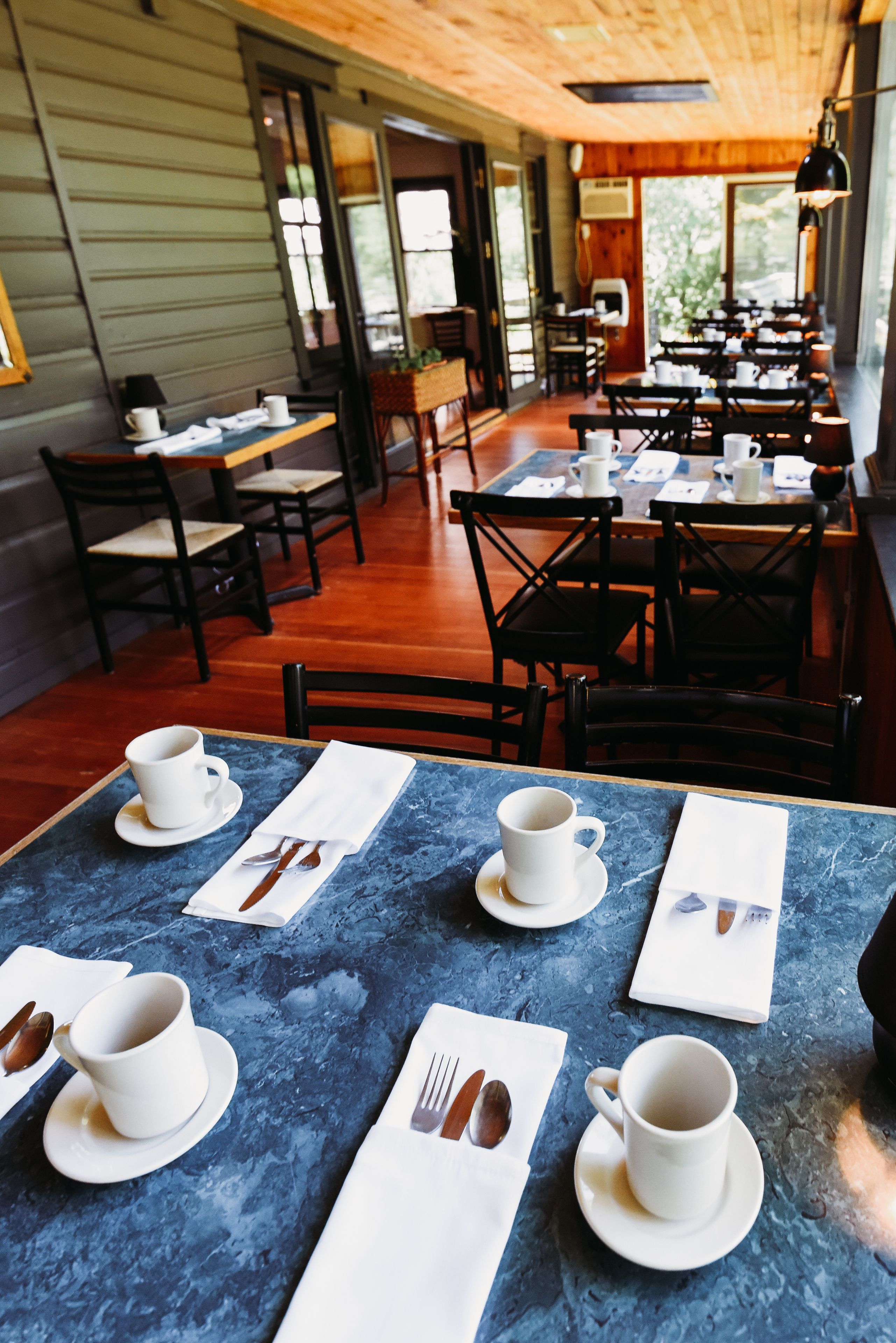 En restaurant med borde dækket til spisning, med blå marmortabledug og hvidt service.