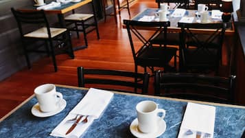 En restaurant med borde dækket til spisning, med blå marmortabledug og hvidt service.