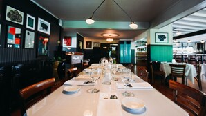 Un restaurante con una larga mesa dispuesta para una comida, mostrando una variedad de platos y copas de vino.