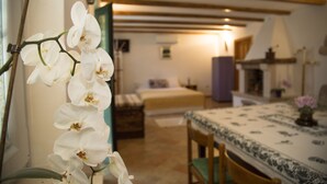 Un dormitorio con cama, una silla, una mesa y una ventana con flores blancas.