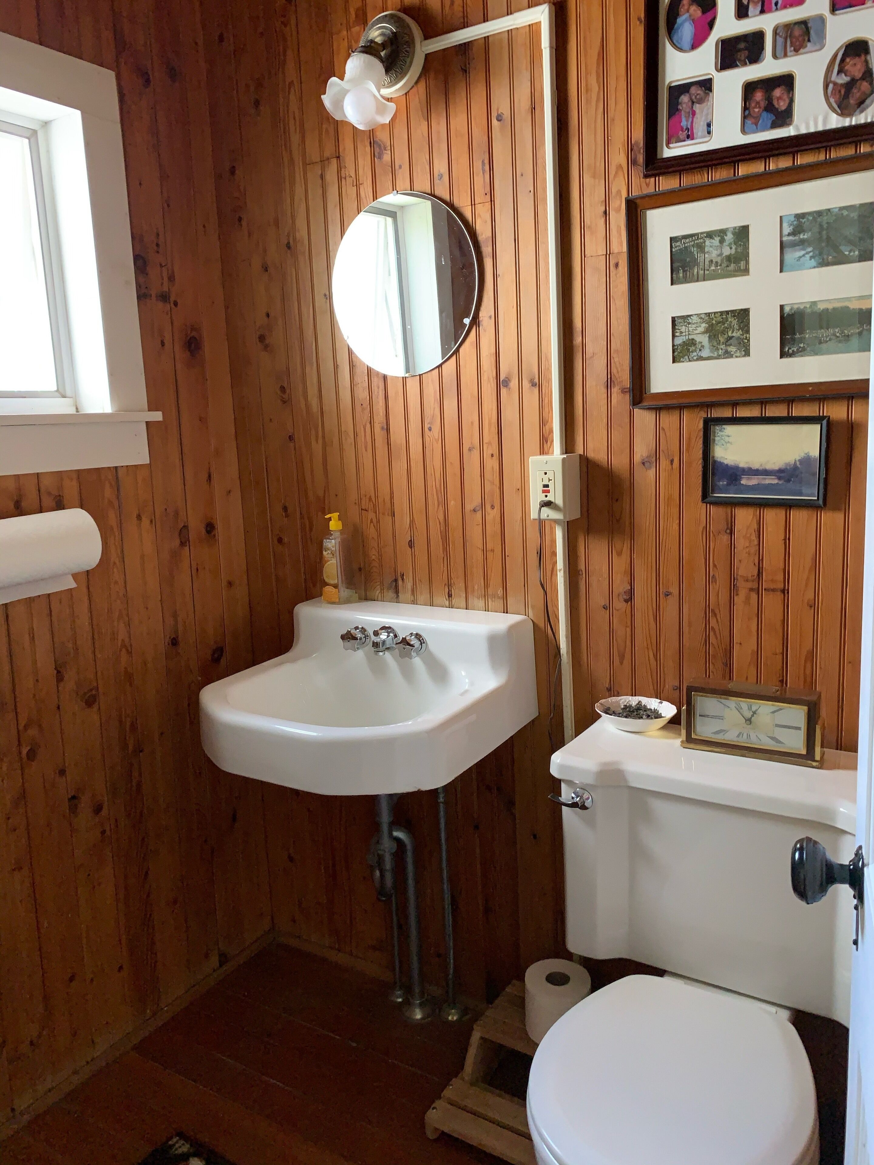 Un baño con paneles de madera, un lavabo blanco, un espejo y un inodoro.