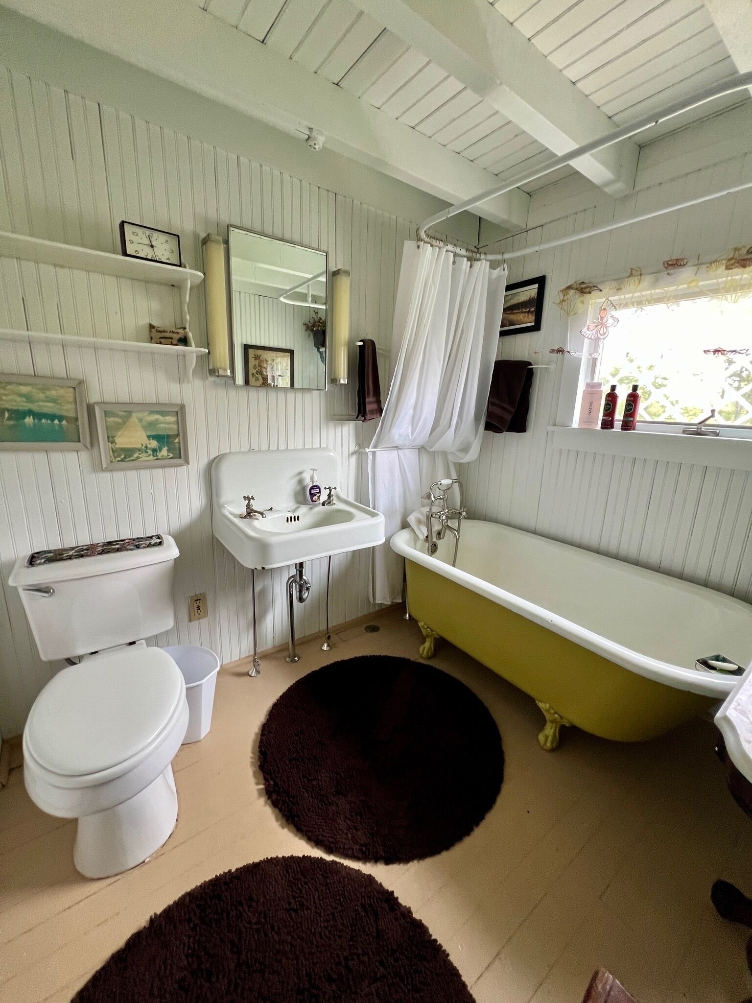 Ein Badezimmer mit Toilette, Waschbecken und Badewanne. Handtücher und Toilettenartikel liegen auf der Ablage am Waschbecken.