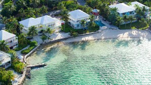 A coastal property with multiple white buildings, a sandy beach, and clear turquoise waters. - 11 steps to the Ocean  (George Town)