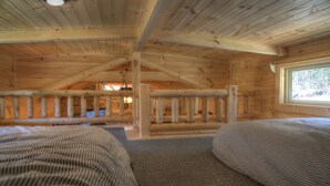 Una cabaña con dos camas, techo de madera y una ventana.