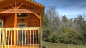 Una cabaña de madera con un porche, una puerta y una ventana.