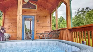 Una cabaña de madera con jacuzzi, una puerta y un ventilador de techo.