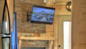 Una cocina compacta con protector contra salpicaduras de piedra, lavavajillas integrado y televisor montado.