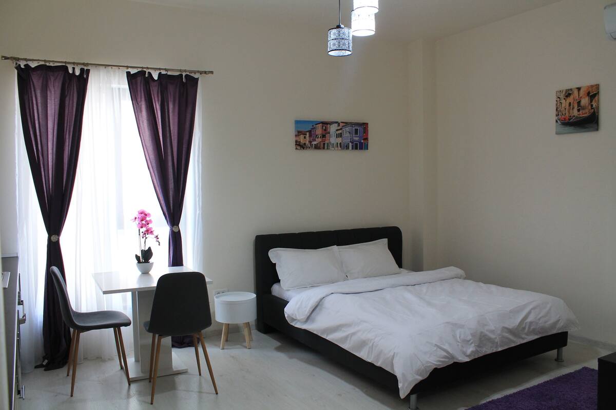 Un dormitorio con una cama, un escritorio y dos sillas.