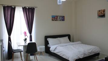 A bedroom with a bed, a desk, and two chairs.