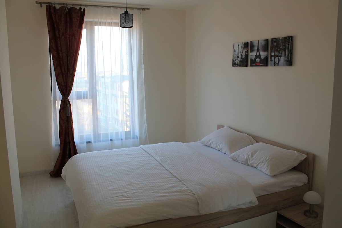 Un dormitorio con cama, cortinas, una lámpara colgante y decoración en las paredes.