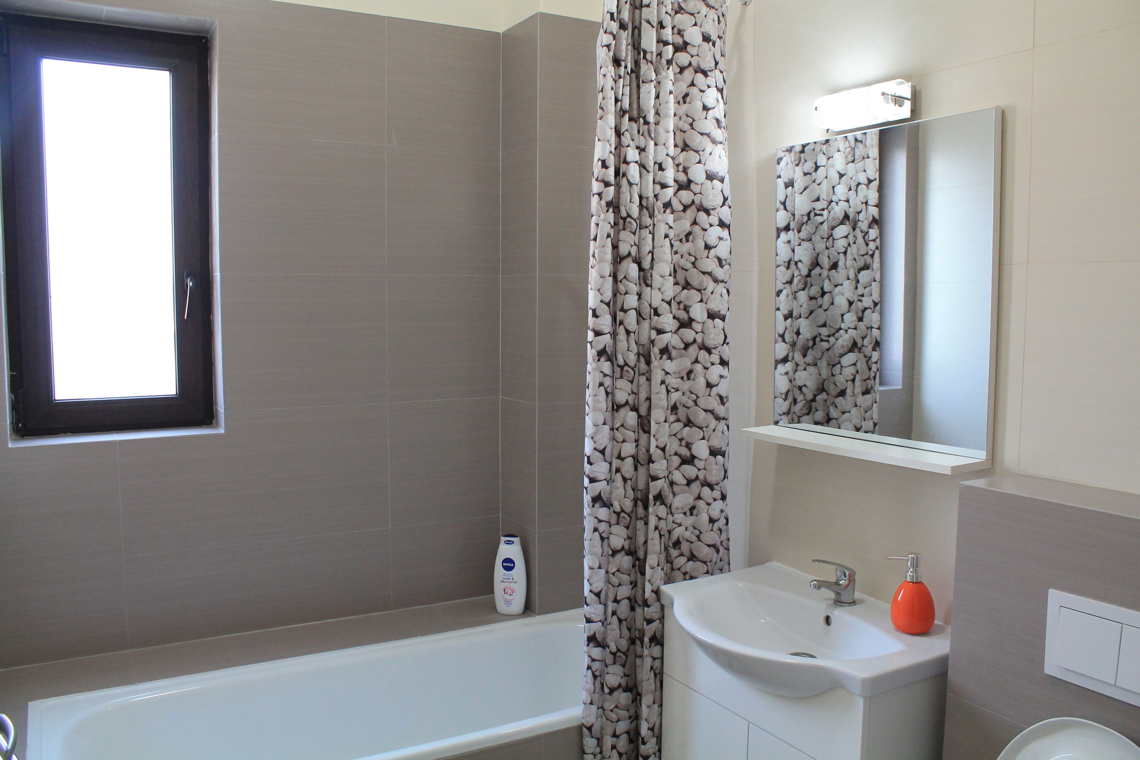 Un baño con bañera, lavabo, espejo y ventana.