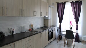 Una cocina moderna con armarios de madera clara, electrodomésticos de acero inoxidable y un comedor con mesa y sillas.