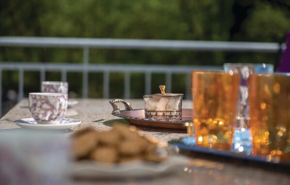 A table set with tea cups, a sugar bowl, and a tray with cookies, outdoors with a railing and greenery in the background. - Awesome apartment in Bribir with WiFi (Bribir)