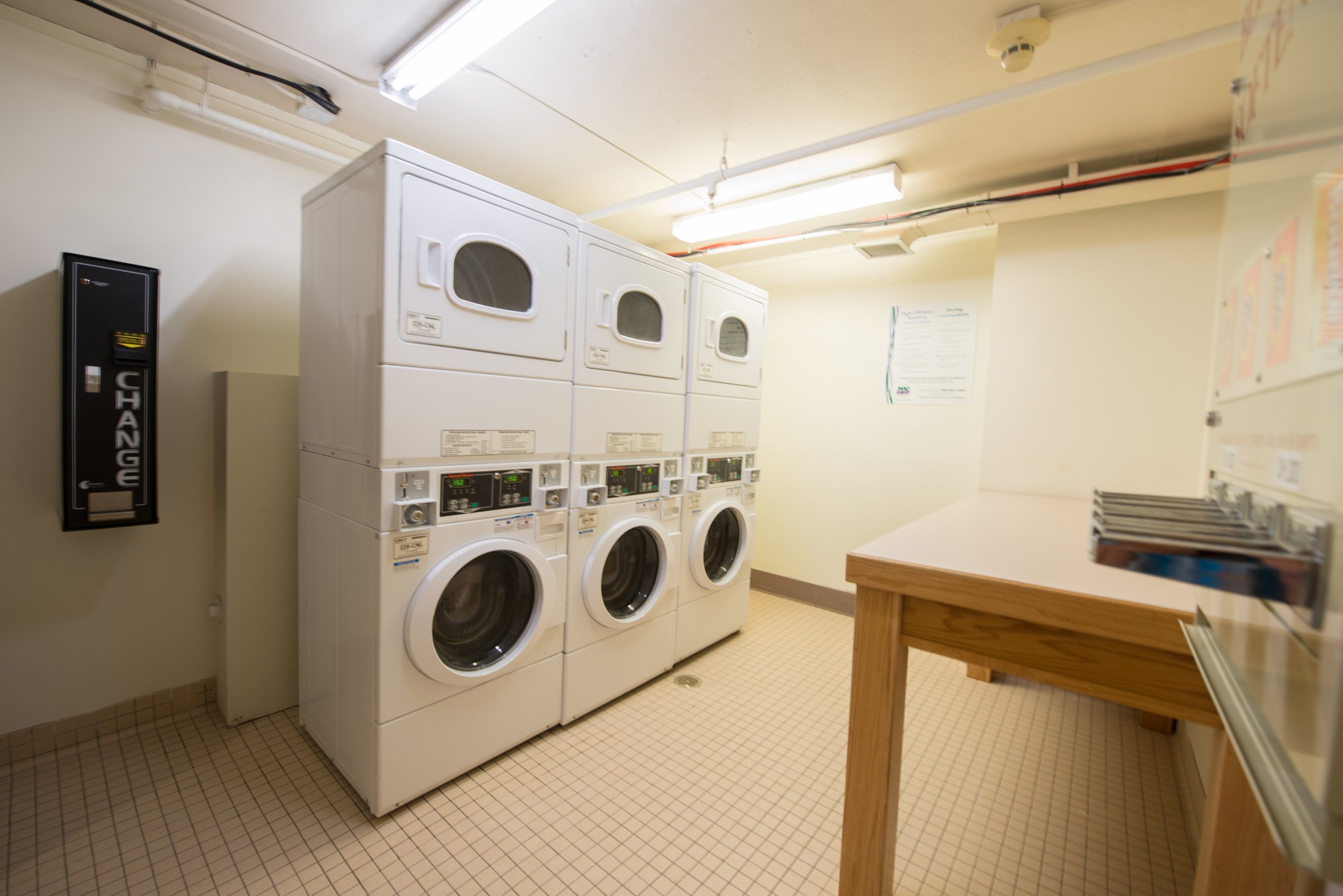 A laundry room with four stacked washing machines and a table with folded clothes.