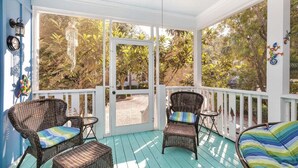 Eine überdachte Veranda mit Korbmöbeln und Blick auf einen Garten.