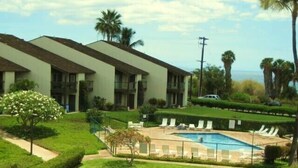 A hotel with a swimming pool, palm trees, and a view of the ocean. - Beachfront//Oceanfront//Ocean View - 1/2/3 Bedroom Kihei Condo (Kihei)