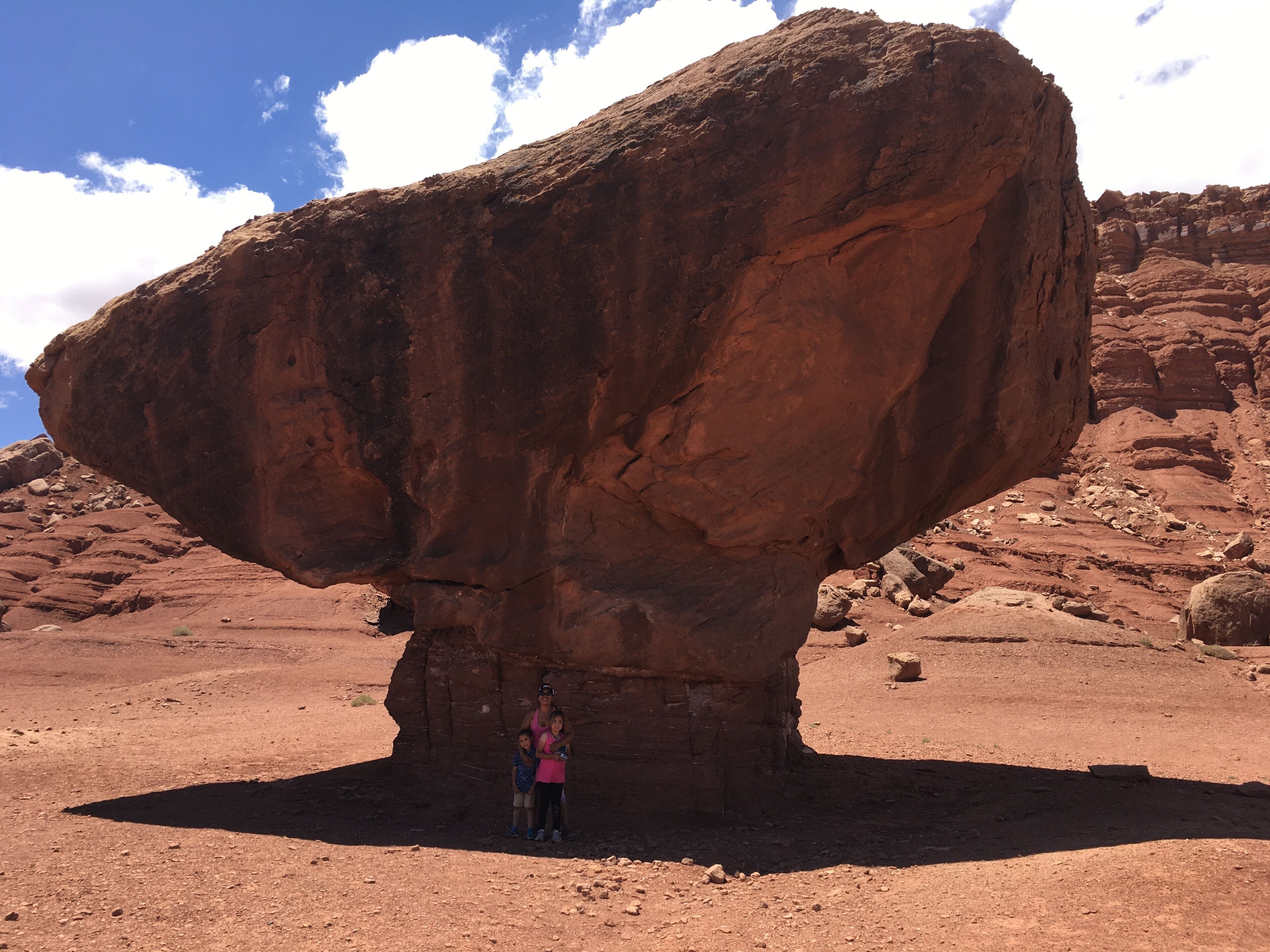 A large rock formation with a person standing underneath it.