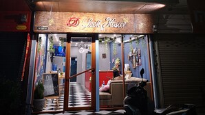 A hotel entrance with a neon sign reading "Luck Hostel" and a checkered floor pattern. - Dluck Hostel (Kanchanaburi)