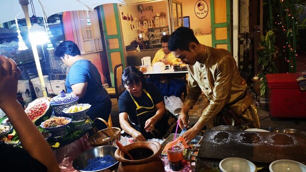 A street food stall with a variety of dishes and cooking utensils. - Dluck Hostel (Kanchanaburi)