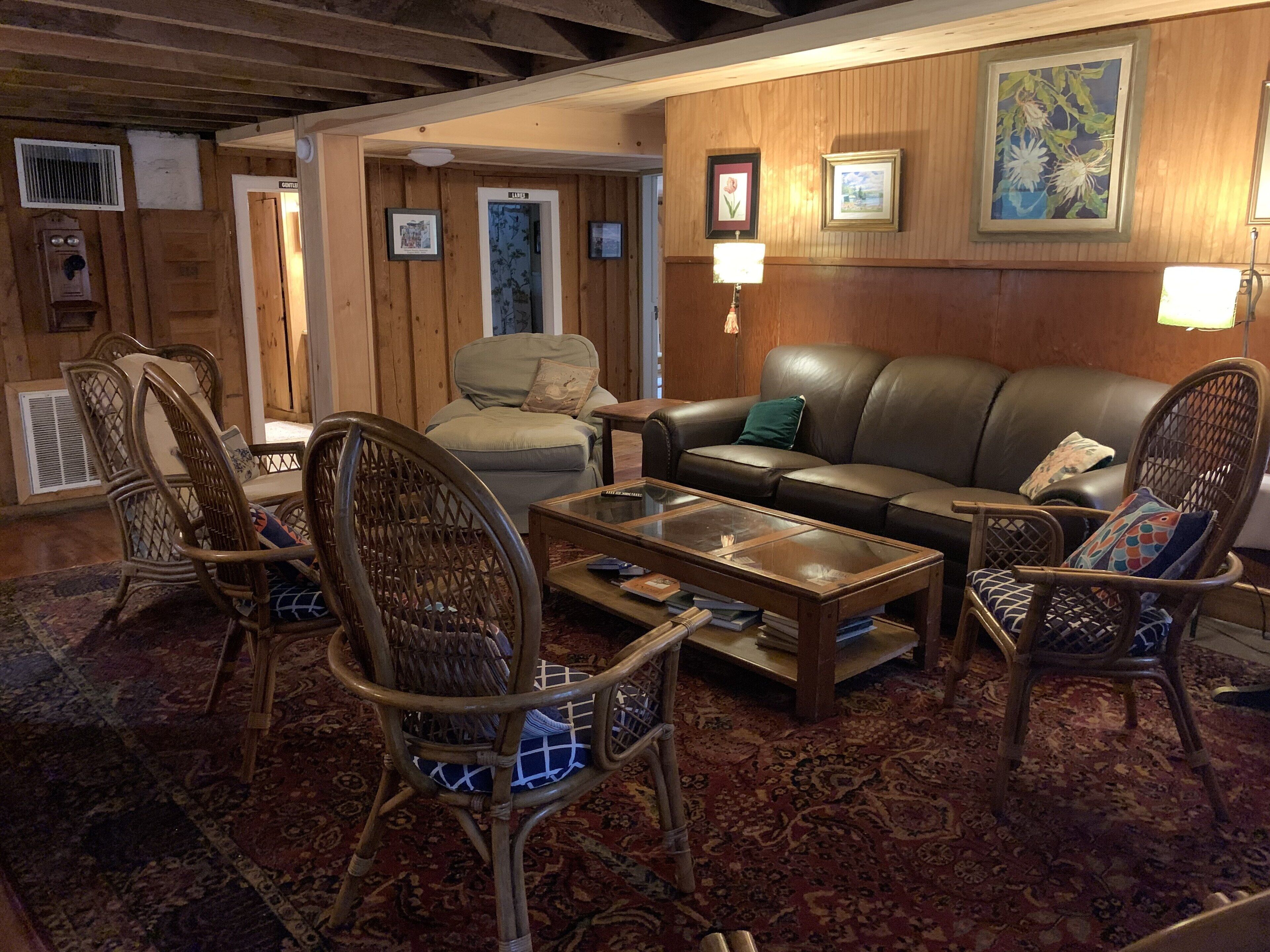A cozy living room with a leather sofa, wicker chairs, a coffee table, and a patterned rug.