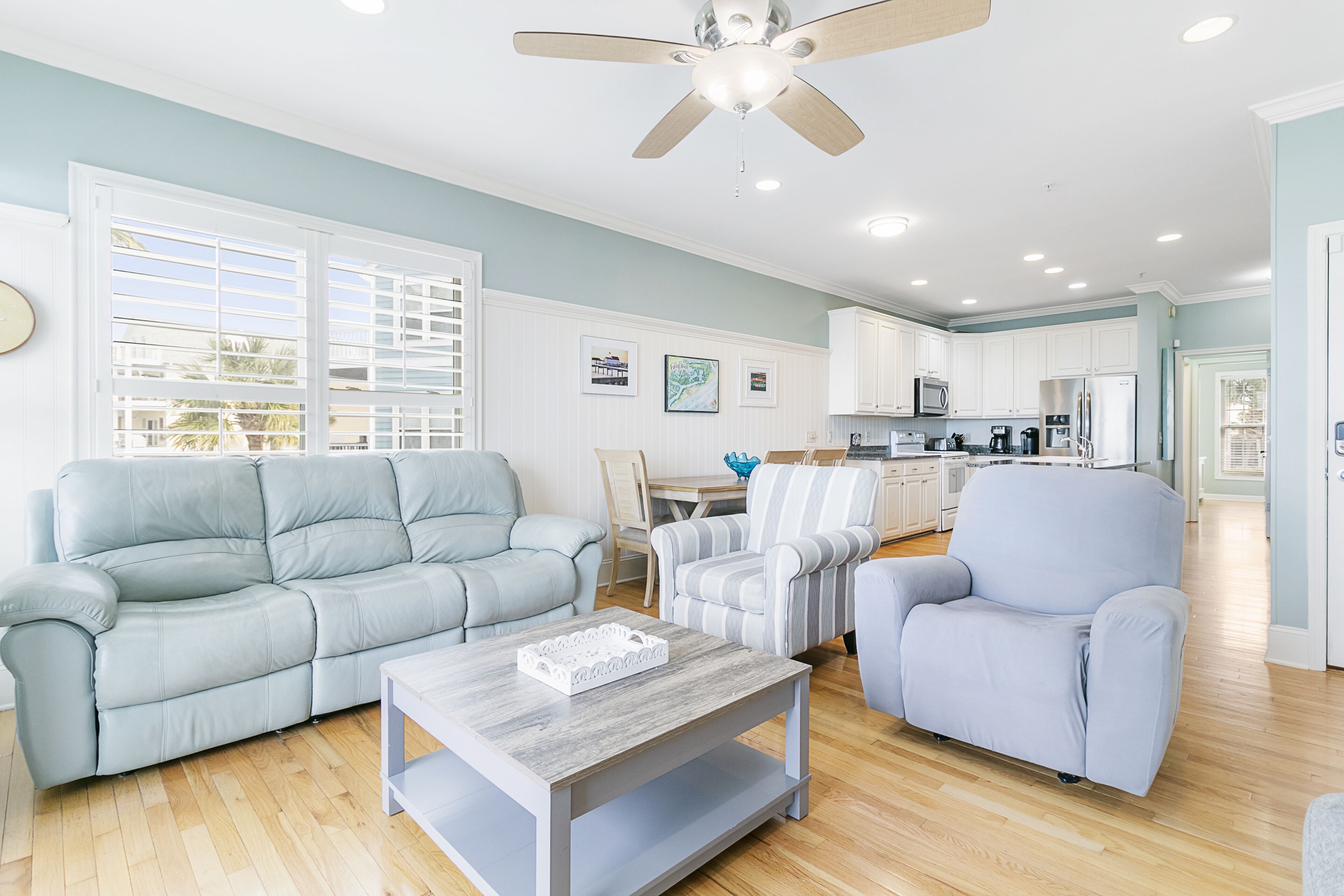 A spacious living room with a light blue sofa, a matching armchair, and a wooden coffee table.