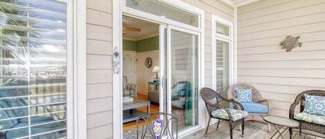 Un patio techado con mobiliario de mimbre y una mesa de azulejos.