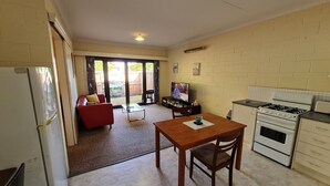 A compact kitchen with a dining area, a red sofa, and a television.