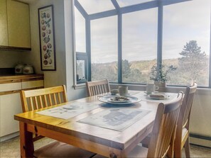 Enjoy meals with a view from this dining area, featuring a table for two and a kitchen with cabinets.