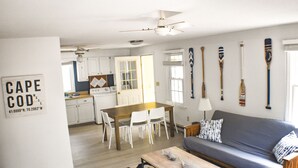 Ein modernes Wohnzimmer mit einer Couch, einem Couchtisch und einem Essbereich mit Stühlen und einem Tisch. An den Wänden befinden sich mehrere Schilder.